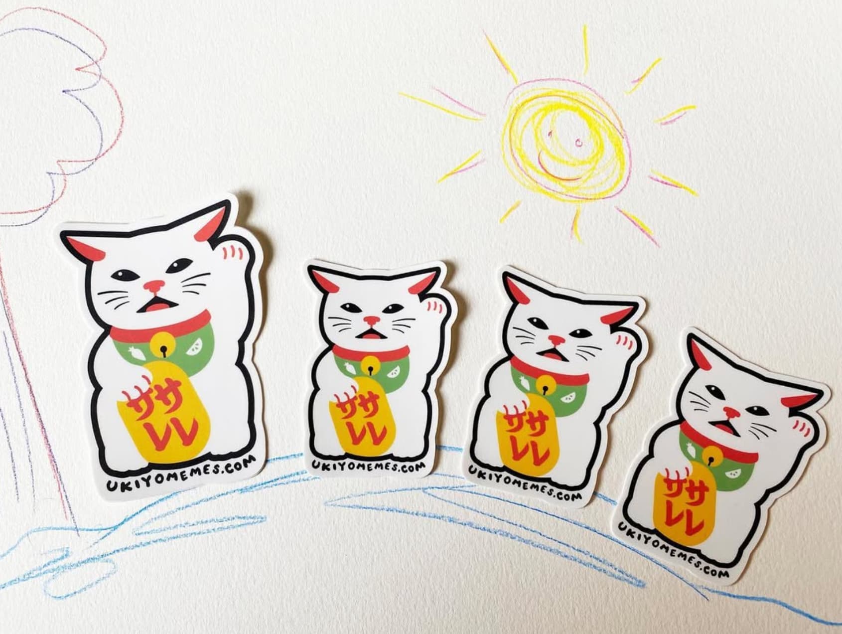 Lucky cat stickers arranged on a crayon doodle